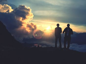 Silhouette people on landscape against sky during sunset