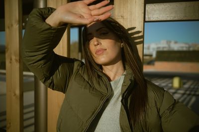 Portrait of young woman standing against wall