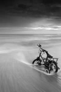 Man riding bicycle on sea against sky