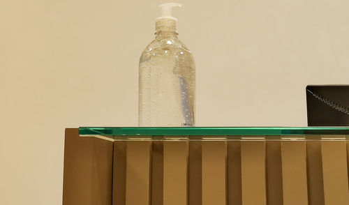 Close-up of glass bottle on table against wall