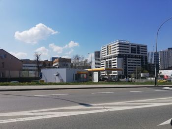 Road by buildings against sky in city