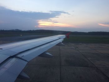 Cropped image of airplane flying over landscape during sunset