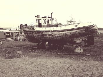 Abandoned boat moored at beach against sky