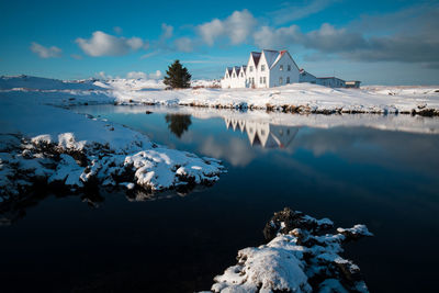 Scenic view of lake by snowcapped mountain against sky