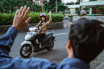 Side view of man riding motor scooter on street