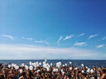 Group of people on beach against blue sky