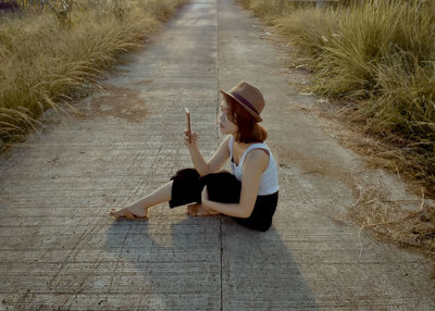 High angle view of woman sitting on footpath