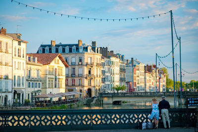 People on bridge against buildings in city