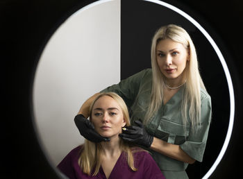 Two beauticians, cosmetologists on white black background. blond hair professionals wear medical