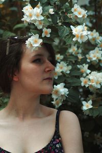 Woman looking away by white flowering plants