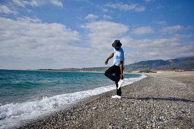 Rear view of man standing on beach against sky