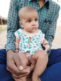 Midsection of father and daughter sitting outdoors