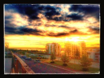 Cars on road against cloudy sky at sunset