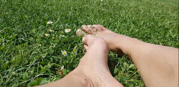 Low section of woman relaxing on grassy field