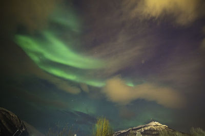 Low angle view of mountains against aurora borealis in sky at night
