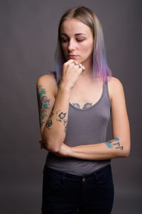 Beautiful young woman standing against gray background