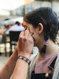 Cropped hands of woman drawing on girl face