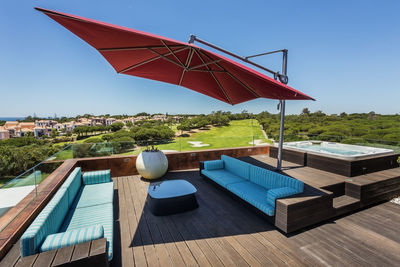 Deck chairs by swimming pool against clear blue sky