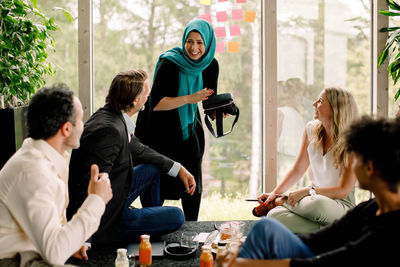 Smiling businesswoman discussing with male and female colleagues during meeting at convention center