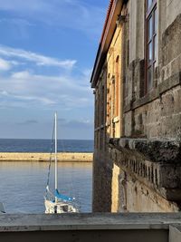 Sailboat on sea by building against sky