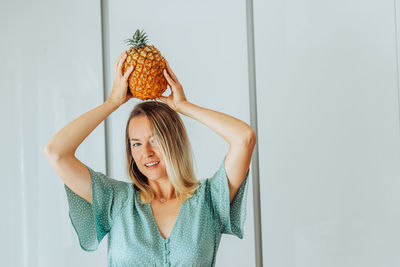 Woman holding azorean pineapple on her head smiling at camera