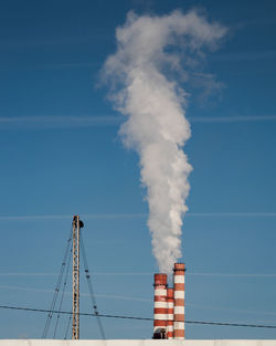 Low angle view of smoke emitting from chimney against sky