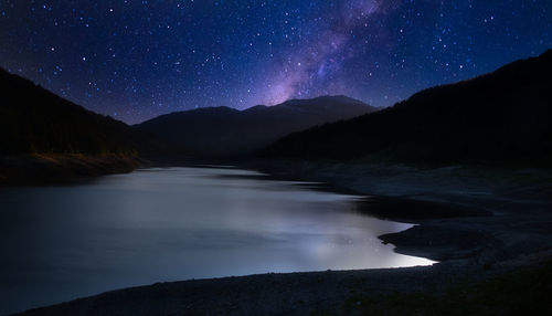 Scenic view of lake and mountains against sky at night