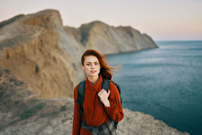 Portrait of young woman standing by sea against sky