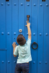 Boy standing against blue door