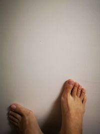 Low section of woman feet on wall