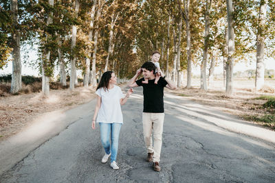 People standing on road along trees