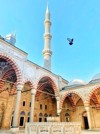 Low angle view of mosque against sky with birds