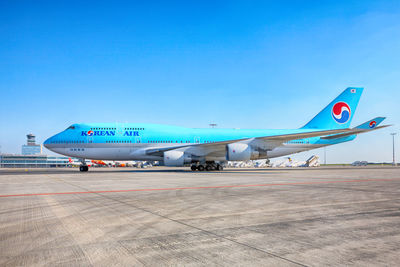 Airplane on airport runway against clear blue sky