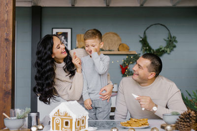 A happy european or american family with a small child stands at the kitchen table at christmas 