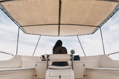 Rear view of woman riding boat against sky