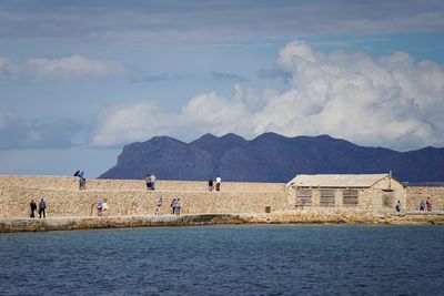 Scenic view of sea by mountains against sky