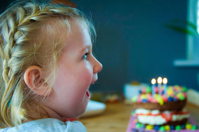 Cheerful girl looking at birthday cake