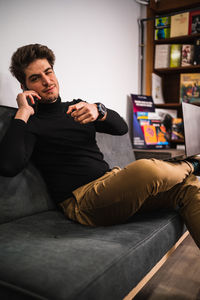 Young man using mobile phone while sitting on sofa at home