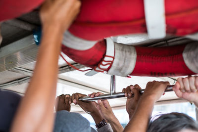 Cropped hand of people holding metal rod in ferry