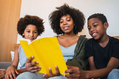 Young woman sitting with boys reading book at home