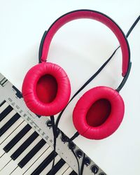 Directly above shot of pink headphones and piano on white background