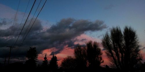 Low angle view of electricity pylon against cloudy sky