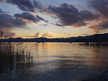 Scenic view of lake against dramatic sky during sunset