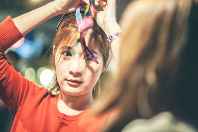 Portrait of young woman wearing bandana while talking with female friend at night