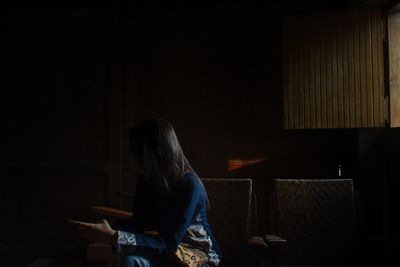 Rear view of woman sitting on chair at home