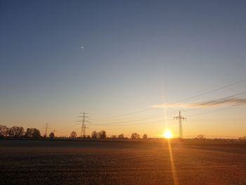 Electricity pylon on field against sky during sunset