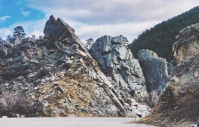 Rock formations by road against cloudy sky