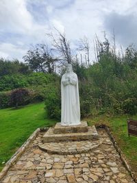 Stone statue in park against sky