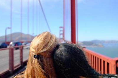 Two women on suspension bridge over sea