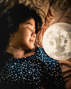 Close-up of woman sleeping by illuminated sphere